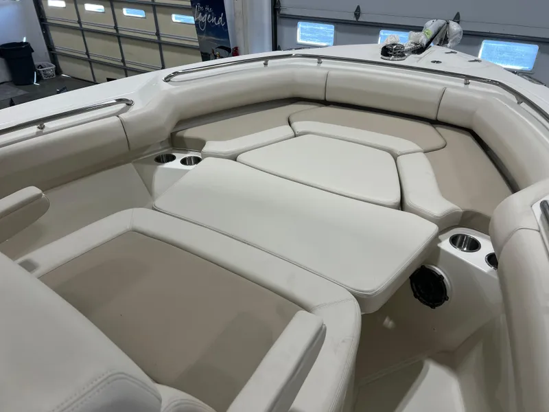 Slide: The Image of 2025 Boston Whaler 250 Outrage boat interior with cushioned seating in a garage. - 18
