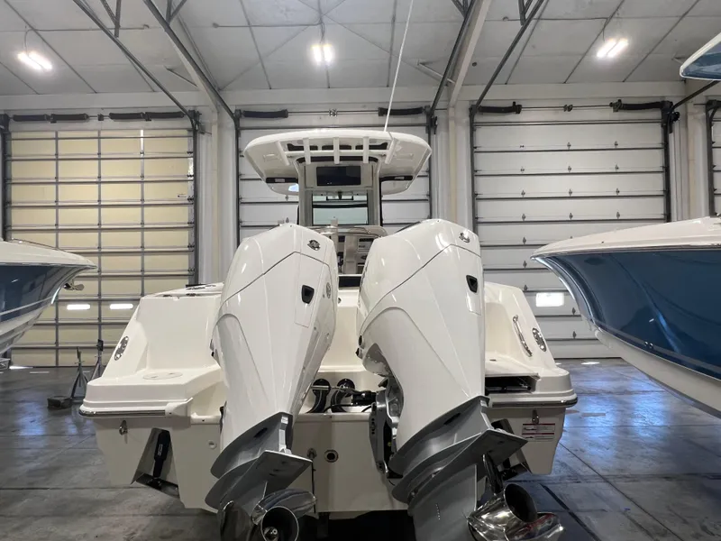 Slide: The Image of 2025 Boston Whaler 250 Outrage with dual engines in a spacious indoor showroom. - 3
