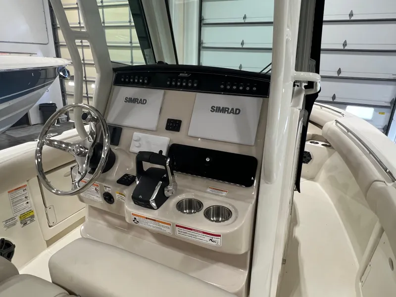 Slide: The Image of 2025 Boston Whaler 250 Outrage boat dashboard with Simrad displays and steering wheel. - 5