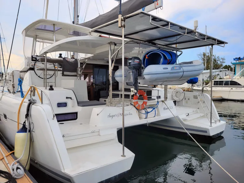 Slide: The Image of 2017 Lagoon 42 catamaran docked, featuring a dinghy and spacious deck. - 11