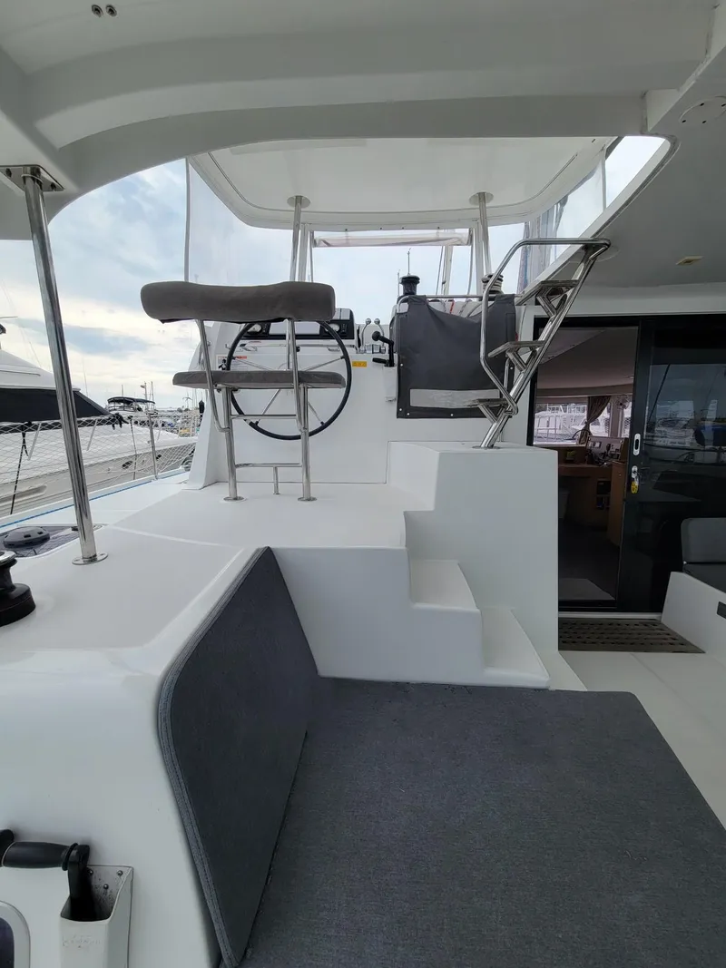 Slide: The Image of Lagoon 42 catamaran (2017) helm station with seating, steps, and marina view. - 12