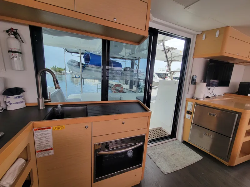 Slide: The Image of Interior of 2017 Lagoon 42 catamaran kitchen with modern appliances and marina view. - 23