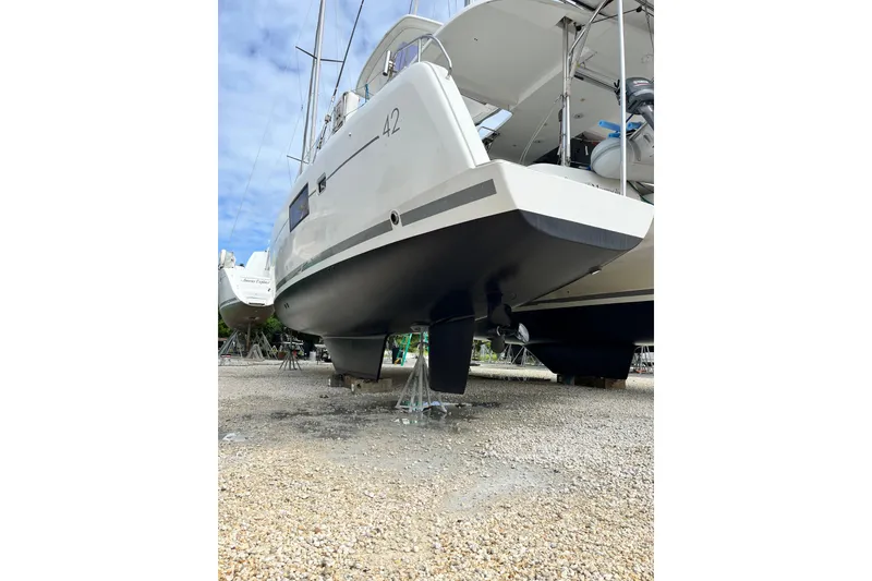 Slide: The Image of 2017 Lagoon 42 catamaran on dry dock, showcasing hull and propeller. - 38