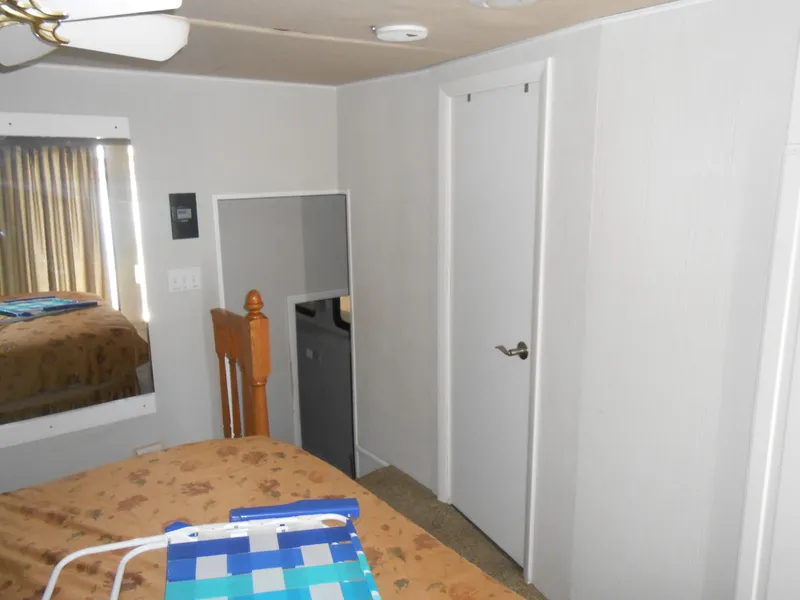 Slide: The Image of Interior of a 2000 Skipperliner Custom Houseboat bedroom with bed, mirror, and door. - 11