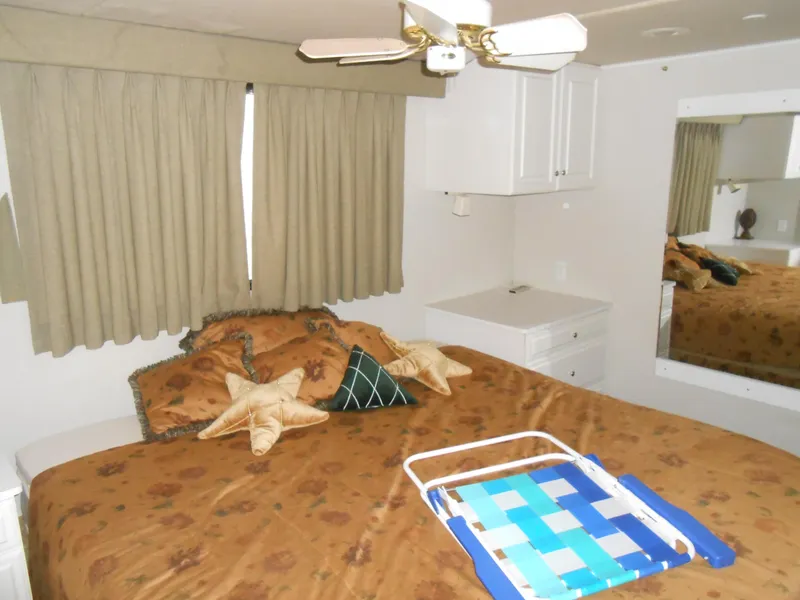 Slide: The Image of Bedroom interior of 2000 Skipperliner Custom Houseboat with bed, ceiling fan, and storage cabinets. - 12