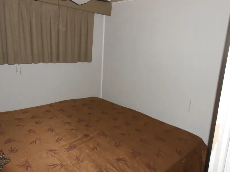 Slide: The Image of 2000 Skipperliner Custom Houseboat bedroom with brown bedspread and beige curtains. - 14