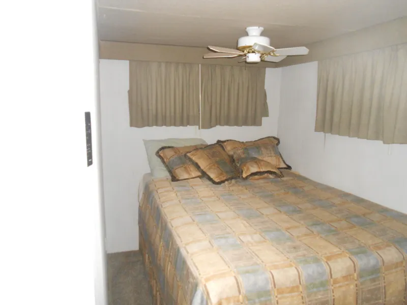 Slide: The Image of Bedroom interior of 2000 Skipperliner Custom Houseboat with bed, pillows, and ceiling fan. - 16