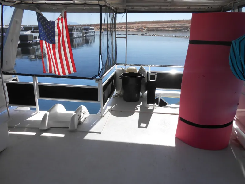 Slide: The Image of Skipperliner 2000 Custom Houseboat deck with American flag and lake view. - 19