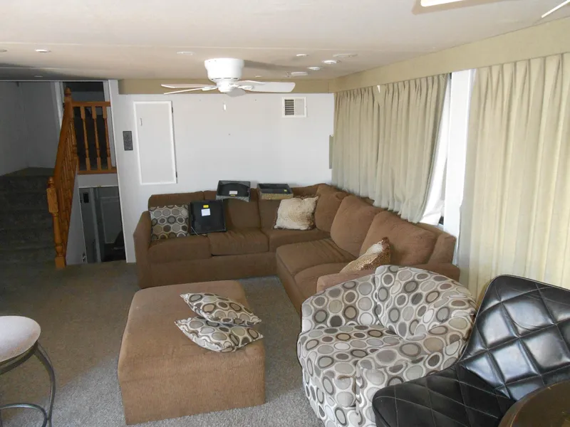 Slide: The Image of Living area of 2000 Skipperliner Custom Houseboat with brown sectional sofa and patterned chair. - 2