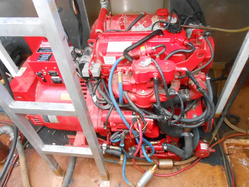 Slide: The Image of Engine room of a 2000 Skipperliner Custom Houseboat with red engine components. - 31