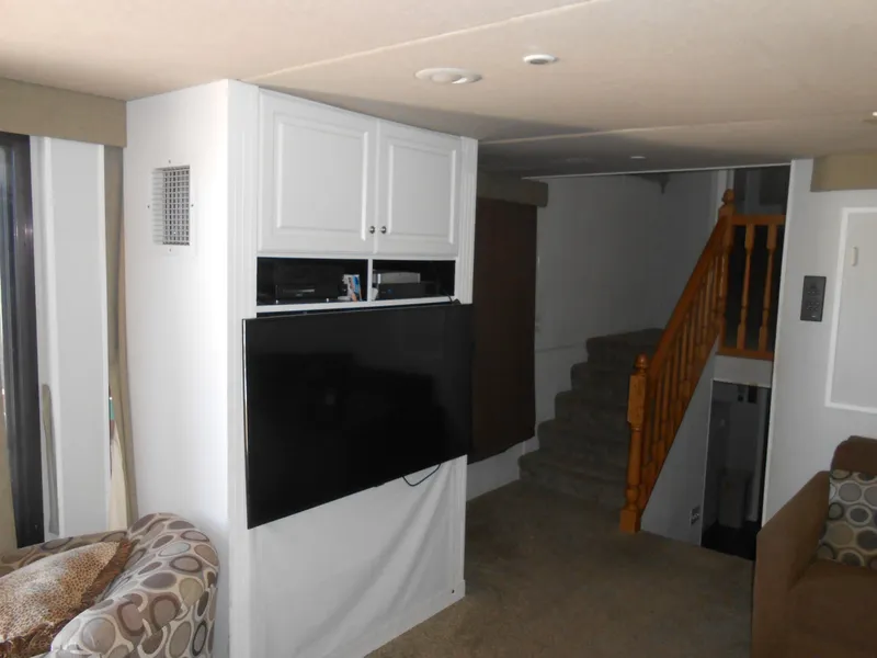 Slide: The Image of Interior of a 2000 Skipperliner Custom Houseboat with TV, stairs, and seating area. - 4