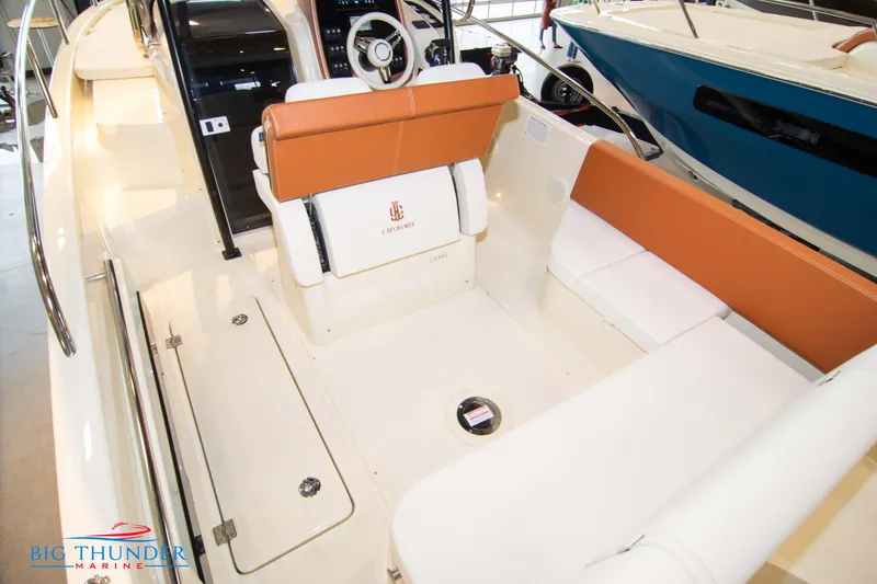 Slide: The Image of 2024 Capoforte CX240 boat interior with white and orange seating, steering wheel, and storage compartments. - 14