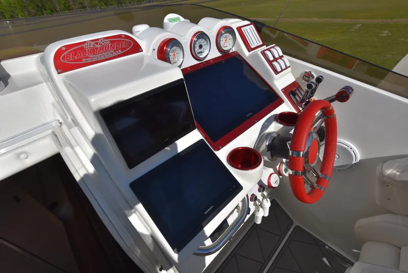 Slide: The Image of 2002 Black Thunder 460 EC boat dashboard with dual screens and red accents. - 15