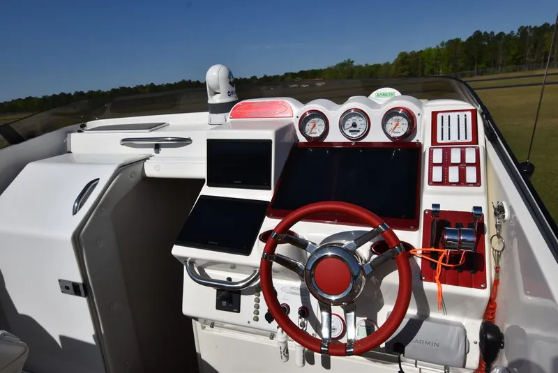 Slide: The Image of 2002 Black Thunder 460 EC boat dashboard with red steering wheel and modern gauges. - 16