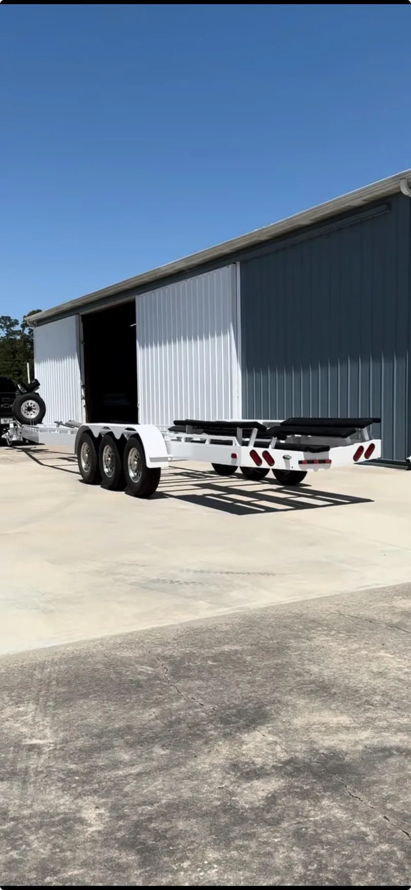 Slide: The Image of 2002 Black Thunder 460 EC boat trailer parked outside a large metal building. - 45