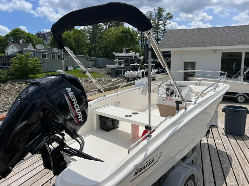 Slide: The Image of 2024 Boston Whaler 130 Super Sport boat docked, featuring a Mercury outboard motor. - 1