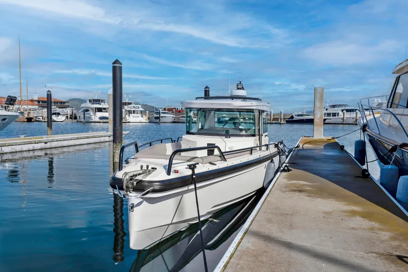 Slide: The Image of 2022 Axopar 28 CABIN boat docked at a marina on a sunny day. - 2