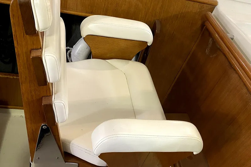 Slide: The Image of White cushioned seat on 1977 Chris-Craft 30 Sportsman boat, featuring wooden paneling. - 13