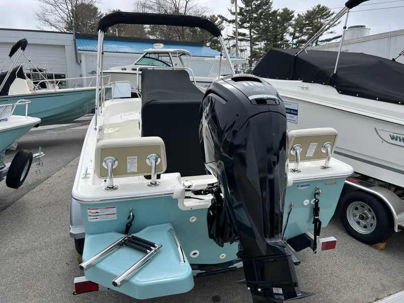 Slide: The Image of 2024 Boston Whaler 170 Montauk boat with outboard motor, docked at marina. - 2