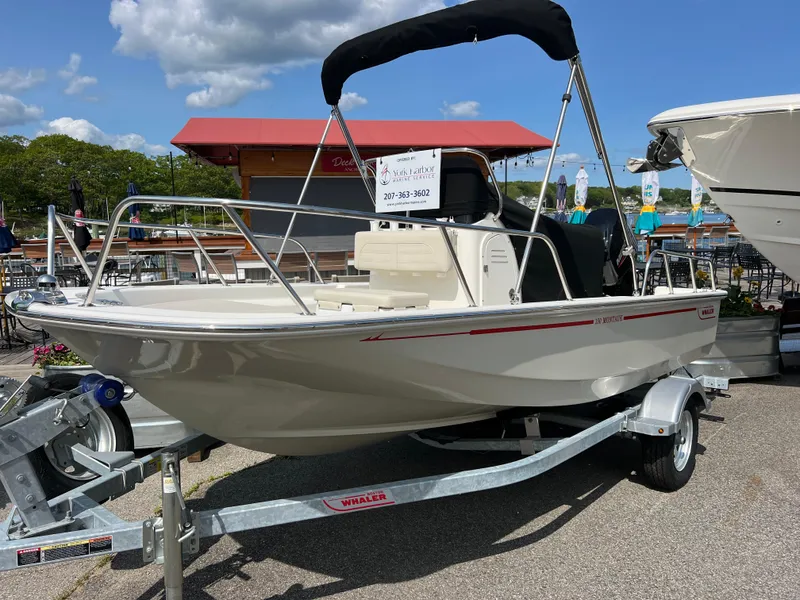 The Image of 2024 Boston Whaler 150 Montauk boat on trailer, displayed outdoors under a blue sky. - 0