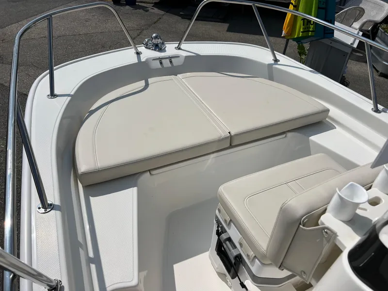 Slide: The Image of 2024 Boston Whaler 150 Montauk boat interior with cushioned seating and stainless steel railings. - 5