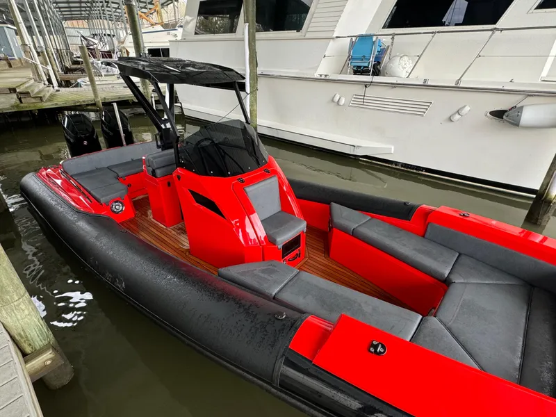 Slide: The Image of Red and black 2024 SuperRib Open 30 boat docked in a marina. - 11