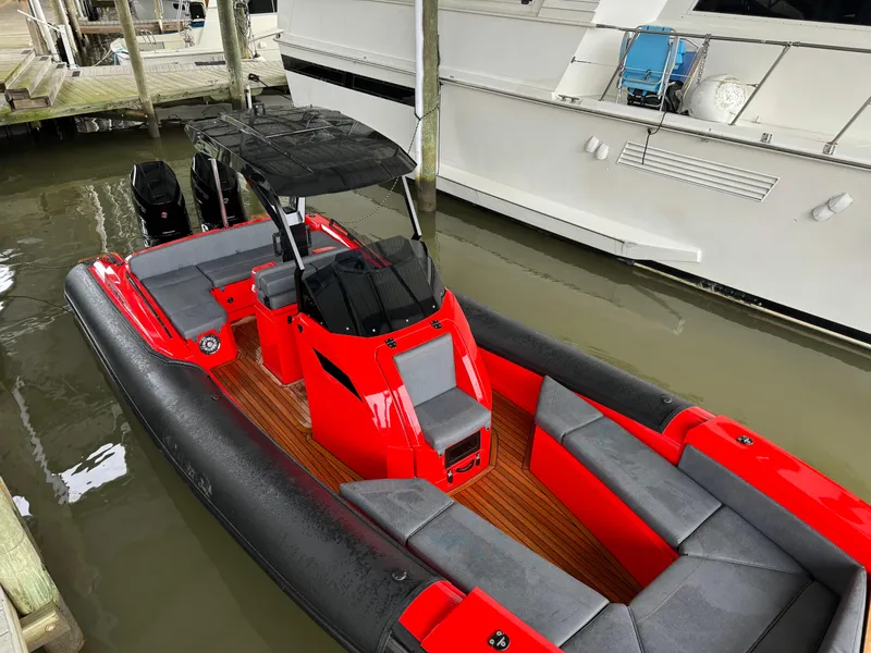 Slide: The Image of 2024 SuperRib Open 30 boat docked, featuring red and black design with spacious seating. - 13