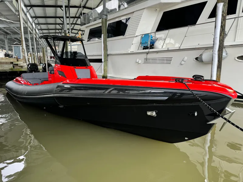 Slide: The Image of 2024 SuperRib Open 30 boat docked, featuring a sleek red and black design. - 14