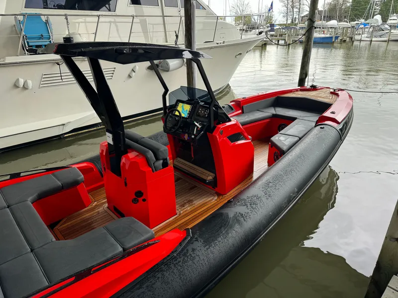 Slide: The Image of 2024 SuperRib Open 30 boat with red and black design docked at marina. - 16