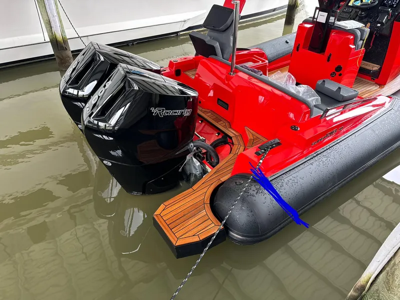 Slide: The Image of Red 2024 SuperRib Open 30 boat with twin black outboard engines docked in water. - 3
