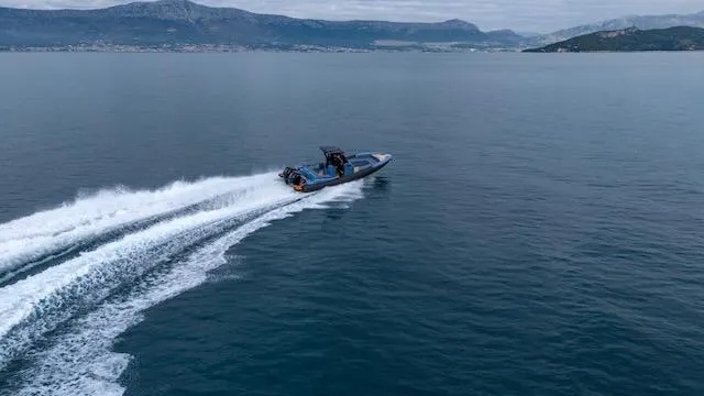 Slide: The Image of 2025 SuperRib Open 30 speedboat cruising on open water with scenic mountain backdrop. - 33