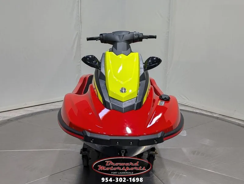 Slide: The Image of 2024 Yamaha EX® Deluxe jet ski, red and yellow, front view in showroom. - 2