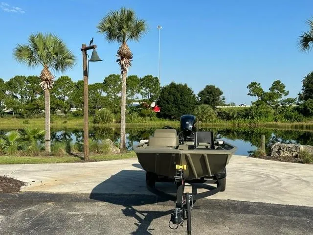 Slide: The Image of 2024 Tracker Grizzly 1754 SC boat on trailer near scenic lake and palm trees. - 2