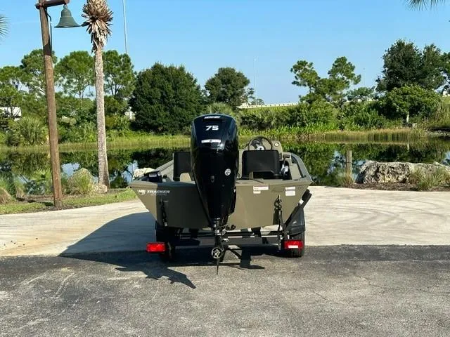 Slide: The Image of 2024 Tracker Grizzly 1754 SC boat with 75 HP motor, parked near a scenic lake. - 3
