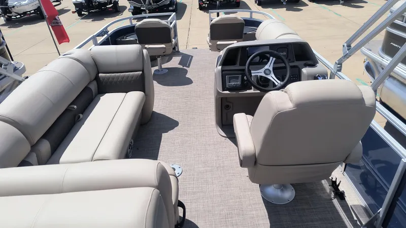 Slide: The Image of 2024 Sun Tracker Fishin' Barge 20 DLX interior with beige seating and steering console. - 2