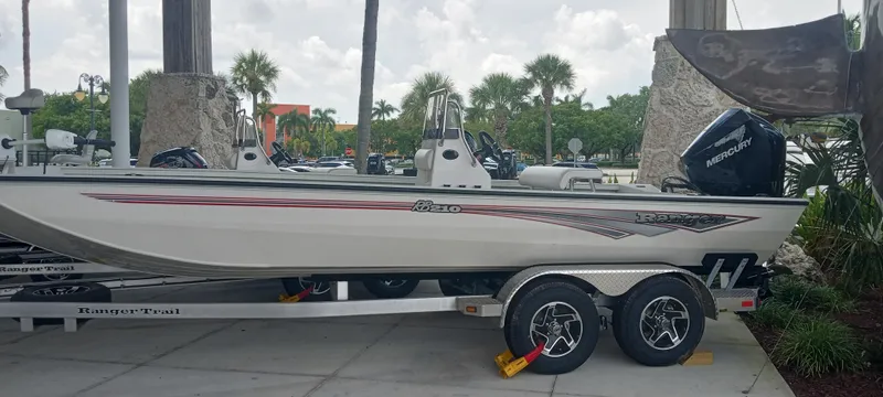 The Image of 2024 Ranger RB210 boat on trailer, parked outdoors with palm trees in background. - 0