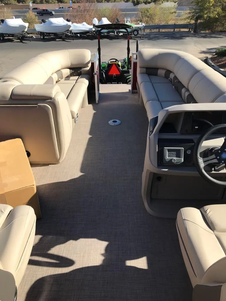 Slide: The Image of 2024 Sun Tracker Party Barge 24 DLX interior with beige seating and steering console. - 10