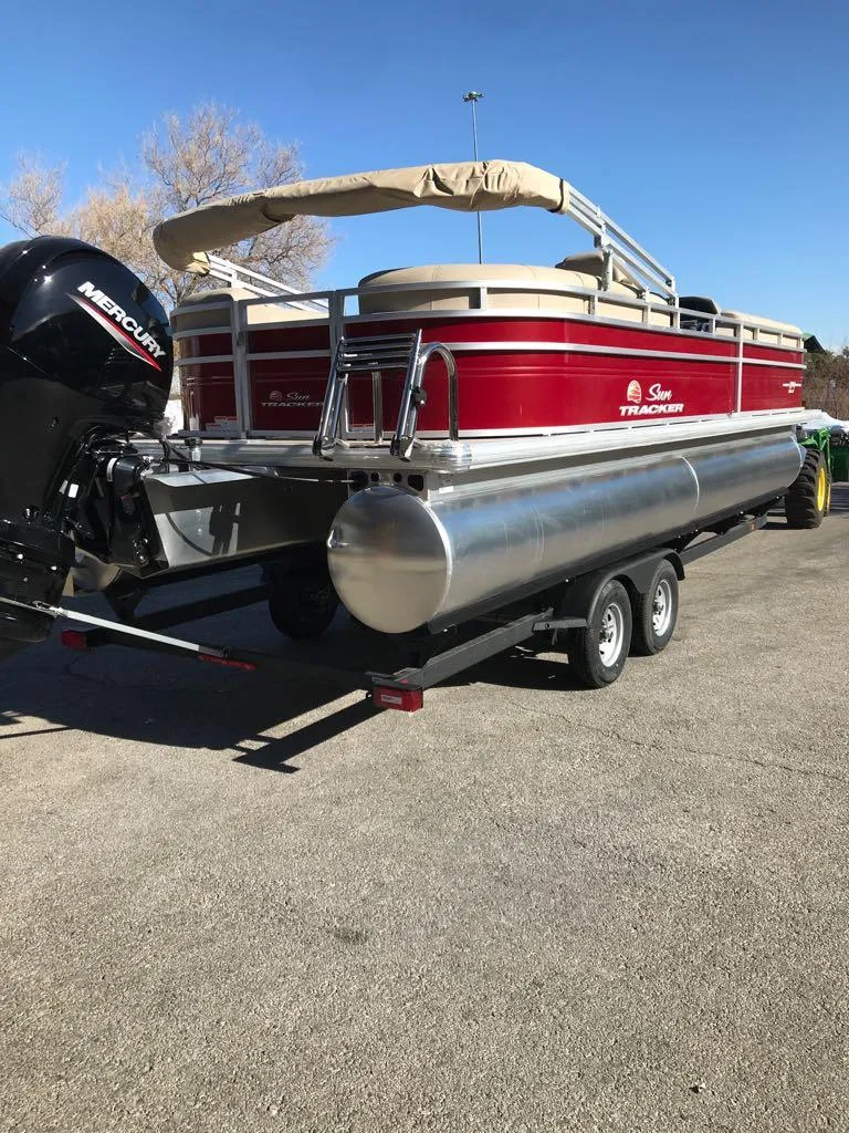 Slide: The Image of 2024 Sun Tracker Party Barge 24 DLX pontoon boat on trailer, red and silver design. - 7
