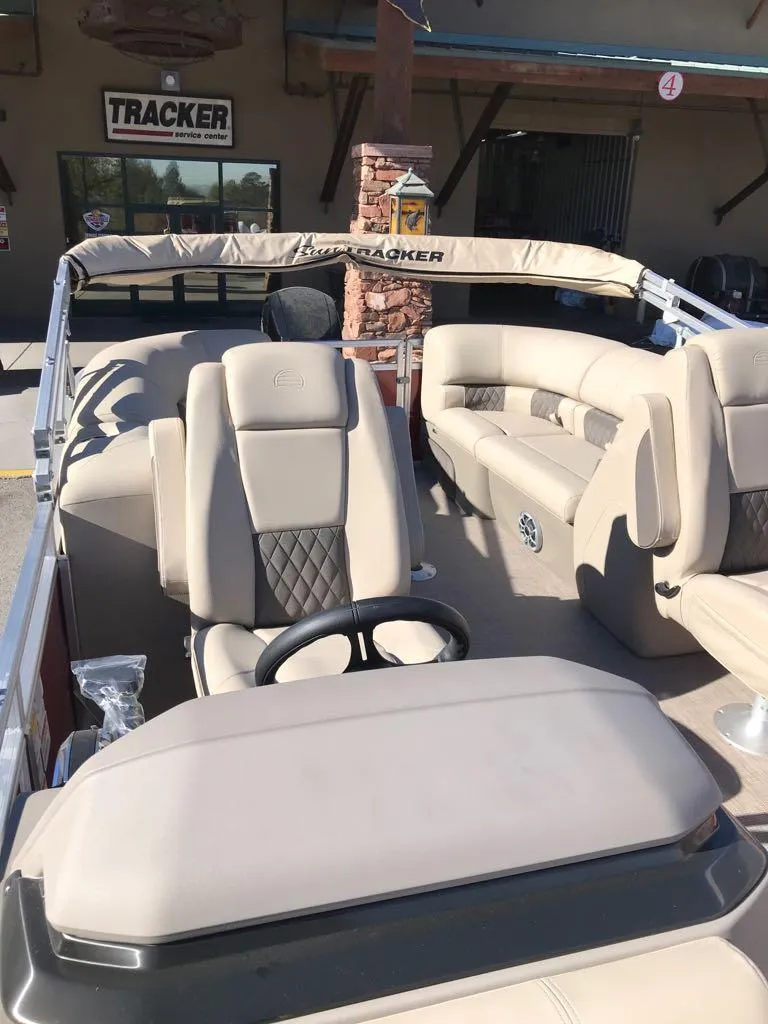 Slide: The Image of 2024 Sun Tracker Party Barge 24 DLX with beige seating and steering wheel. - 8
