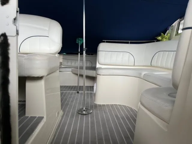 Slide: The Image of Interior of a 2000 Rinker 310 Fiesta Vee boat with white seating and blue canopy. - 11