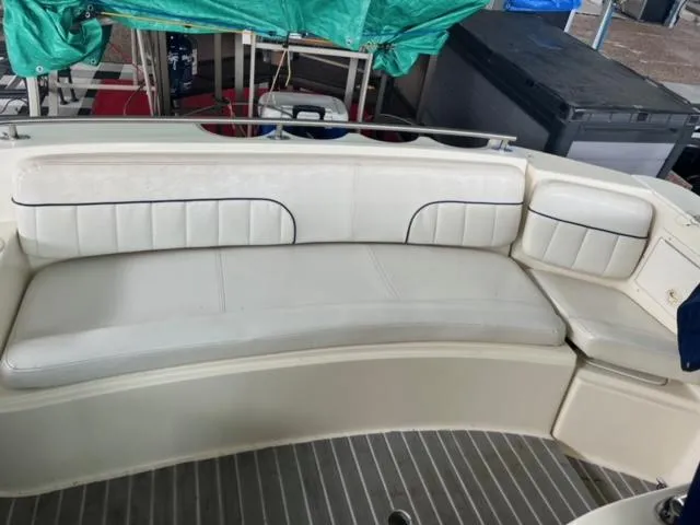Slide: The Image of 2000 Rinker 310 Fiesta Vee boat interior seating area with white cushioned bench. - 13