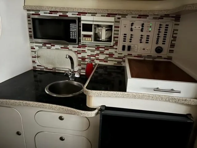 Slide: The Image of Compact kitchen area in a 2000 Rinker 310 Fiesta Vee boat with microwave and sink. - 19