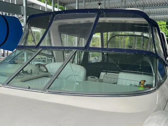 Slide: The Image of 2000 Rinker 310 Fiesta Vee boat with blue canopy in covered dock. - 2