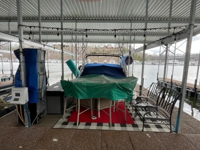 Slide: The Image of Covered 2000 Rinker 310 Fiesta Vee docked under a metal canopy by the water. - 9