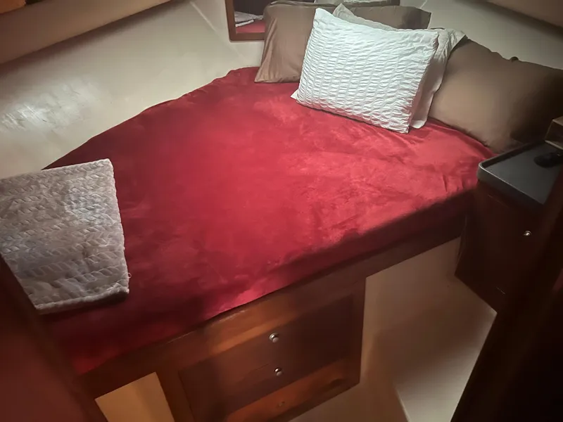 Slide: The Image of 2001 Luhrs 34 Convertible cabin with red bedding and pillows. - 24