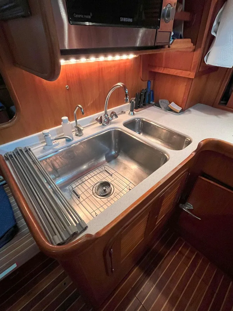 Slide: The Image of 2001 Hinckley Sou'wester 59 CC yacht kitchen sink area with modern fixtures and wood cabinetry. - 34