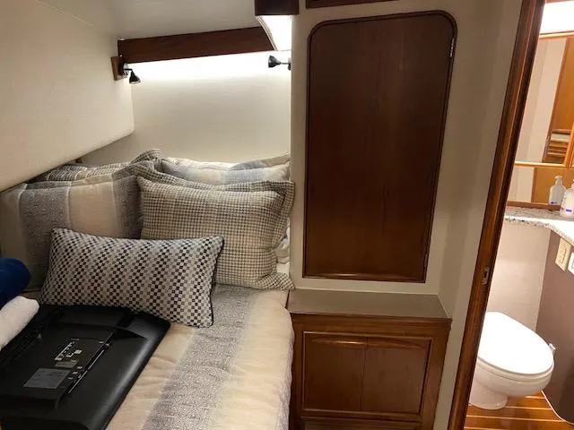 Slide: The Image of 1984 Custom Carolina Buddy Davis cabin with bed, pillows, wooden cabinets, and adjacent bathroom. - 22
