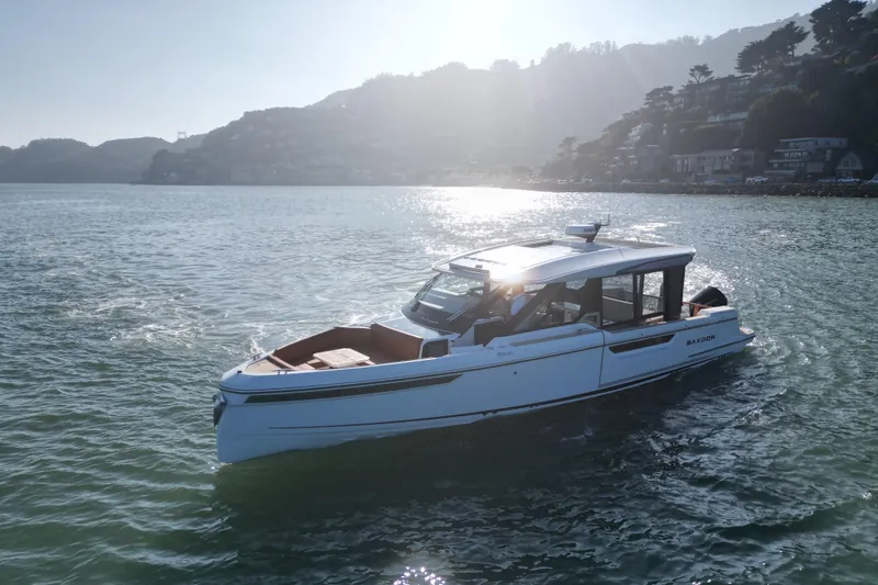 Slide: The Image of 2026 Saxdor 400 GTC boat cruising on a sunny day near a scenic coastline. - 20