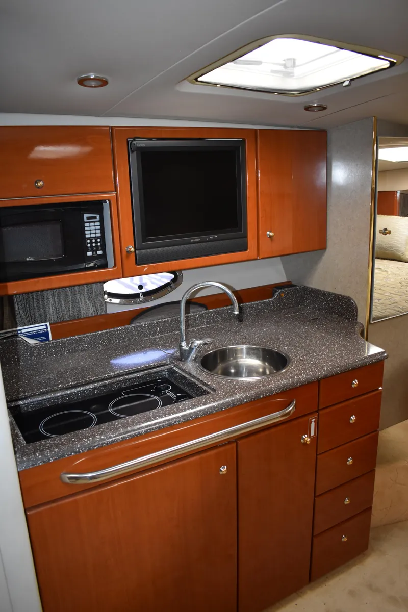 Slide: The Image of 2004 Formula 34 PC yacht kitchen with wood cabinets, sink, stove, and microwave. - 12