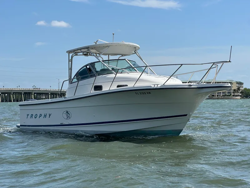 Slide: The Image of 1998 Trophy 2902 Walkaround boat on water, clear sky background. - 2
